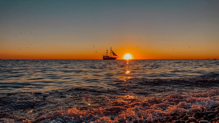 Ship sailing at sunset over the ocean
