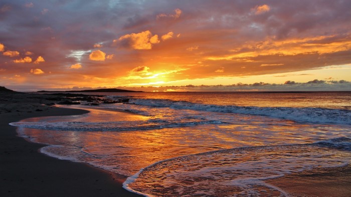 Sunset over a beach with waves
