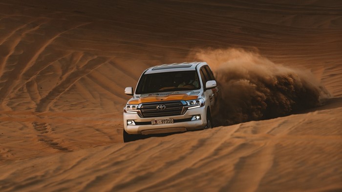Toyota Land Cruiser driving through desert dunes
