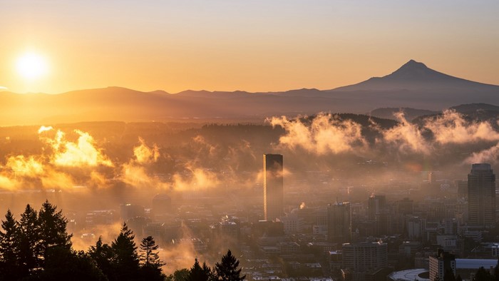 Cityscape at sunrise with mountains and fog