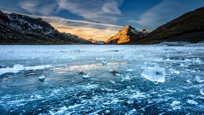 Frozen lake with mountains at sunset