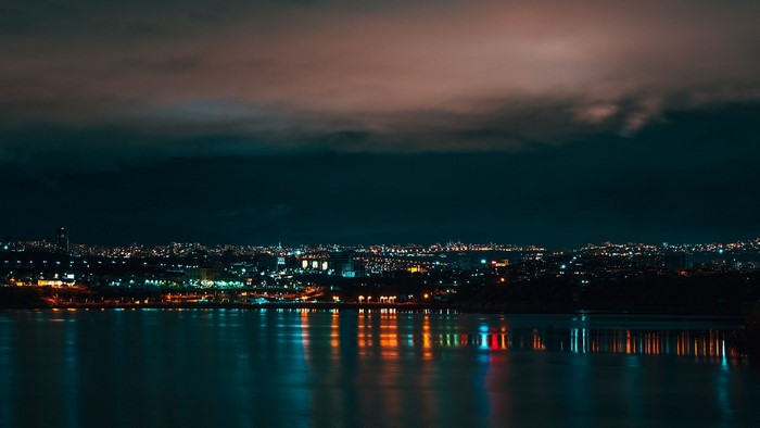 Night city skyline over water with reflections