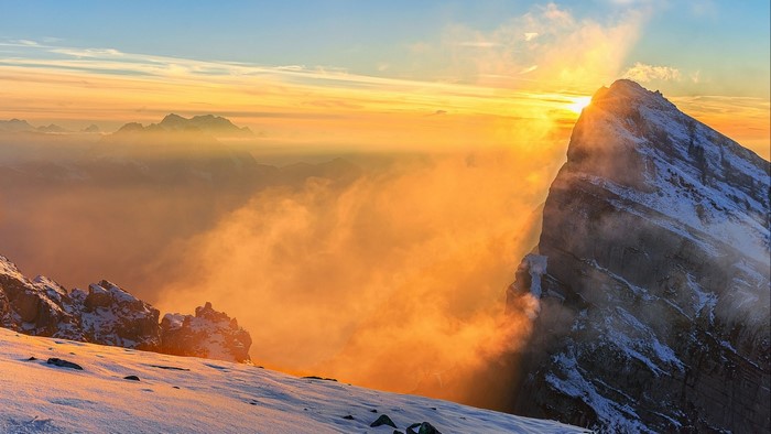 Sunrise over snowy mountains with clouds
