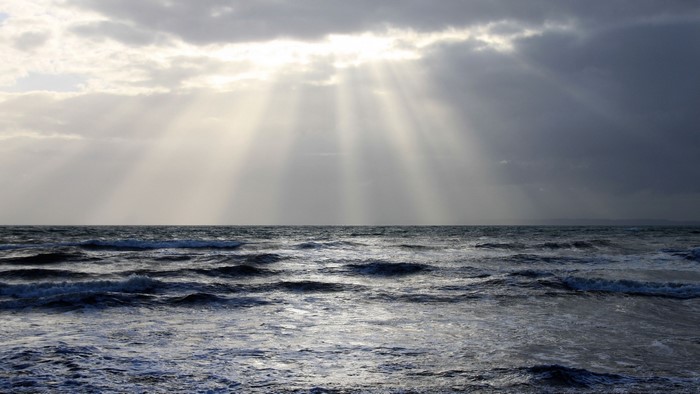 Sunbeams through clouds over ocean waves