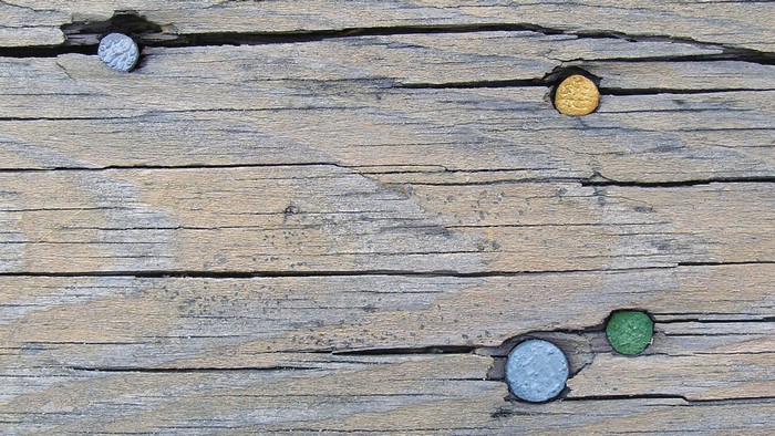 Old wooden board with colored nails