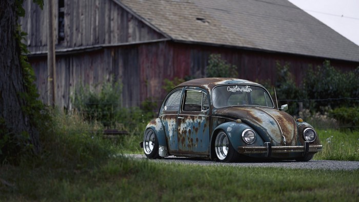Rusty Volkswagen Beetle parked by a barn