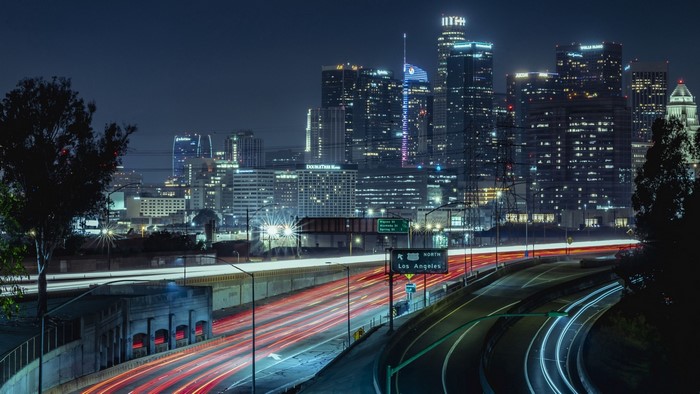 Nighttime Los Angeles cityscape with light trails on highway