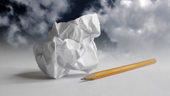 Crumpled paper and pencil against stormy sky