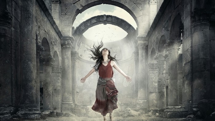 Woman with arms outstretched in ancient ruins