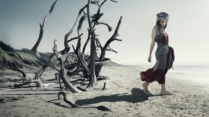 Girl walking on a beach with driftwood