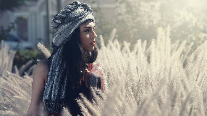 Woman wearing a headscarf in a field of tall grass