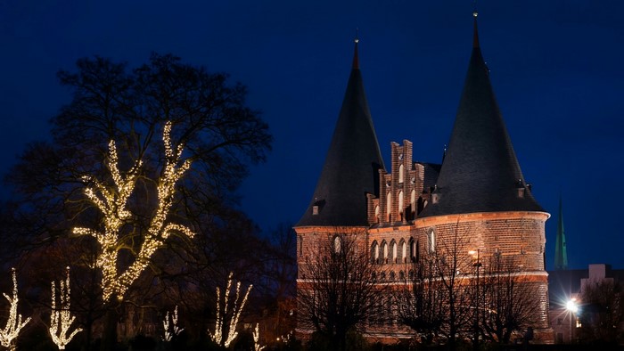 Brick gate towers with conical roofs decorated with lights at night