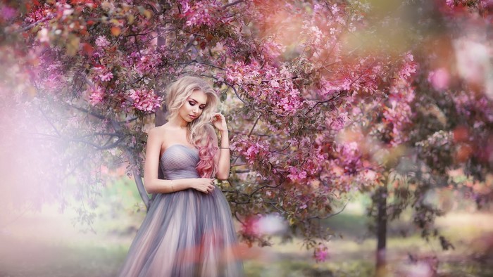 Woman in a flowing dress among pink blossoms