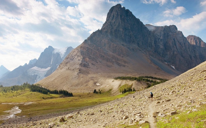 Hiker on a rocky mountain trail with glaciers in the background