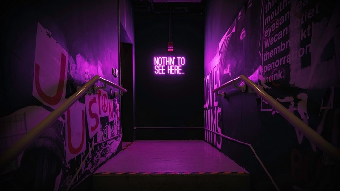 Neon sign 'Nothin to see here' in a hallway