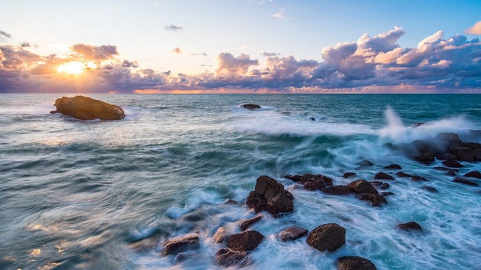 Ocean waves crashing on rocks at sunset