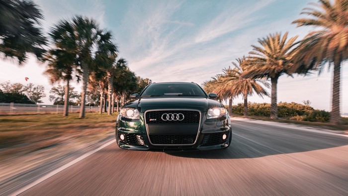 Audi RS4 driving on a road lined with palm trees
