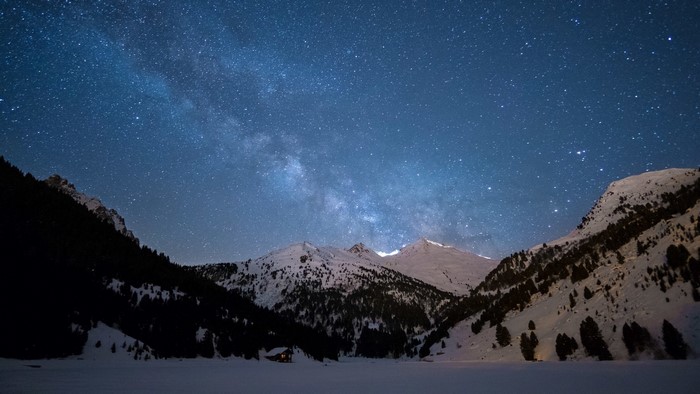 Starry night sky over snow-covered mountains