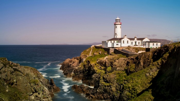 White lighthouse on a rocky cliff overlooking the ocean