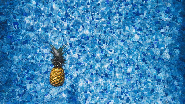 Pineapple floating in a swimming pool