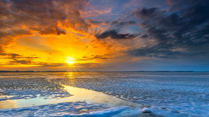 Sunset over a frozen lake with dramatic clouds