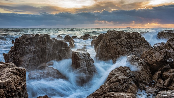 Waves crashing on rocky shore at sunset