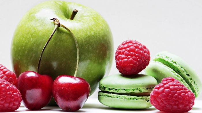 Still life with green apple, cherries, raspberries, and macarons