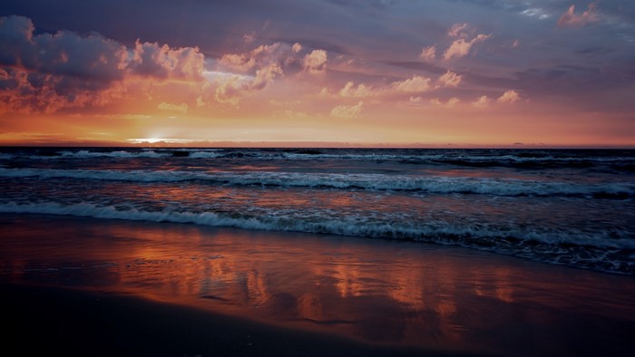 Sunset over the ocean with waves and beach