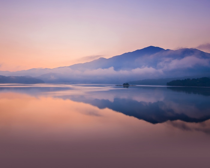Sunset over a misty lake with mountains and reflections