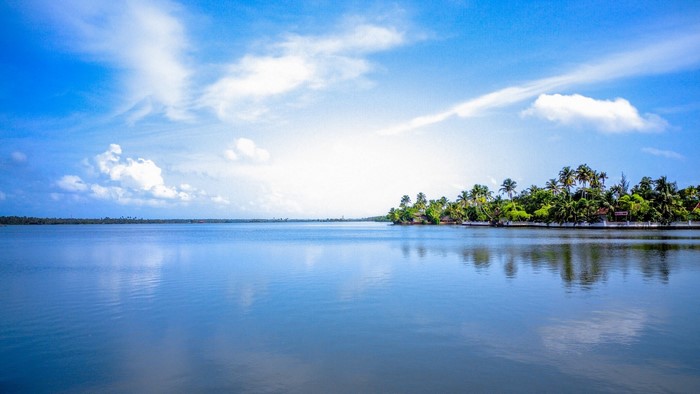 Island with palm trees on a lake under a blue sky