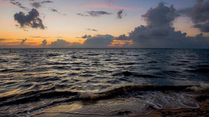 Ocean waves at sunset with clouds