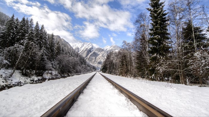 Snowy railway tracks leading to snow-covered mountains