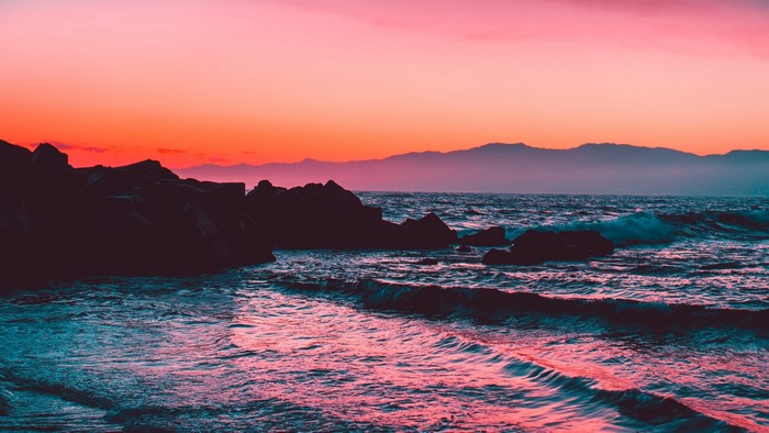 Ocean waves crashing on rocks at sunset