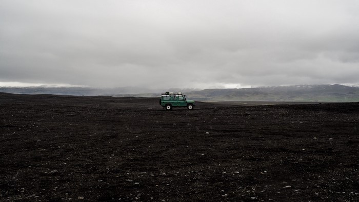 Green Land Rover Defender in a desolate landscape
