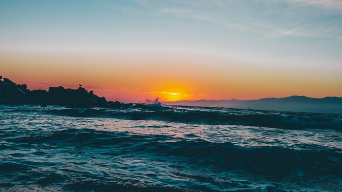 Ocean waves at sunset with rocky shore