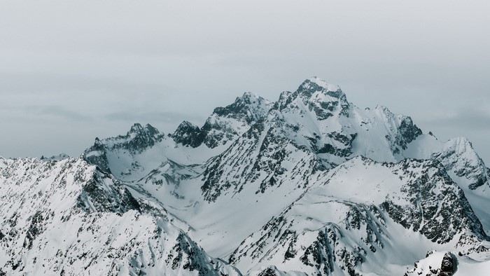 Snow-covered mountain peaks under a cloudy sky