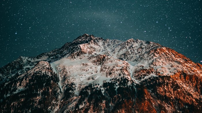 Snow-covered mountains under a starry night sky