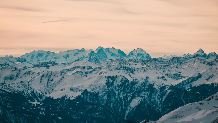 Snow-covered mountain range under a pale sky