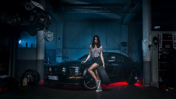 Woman posing with a car in a garage