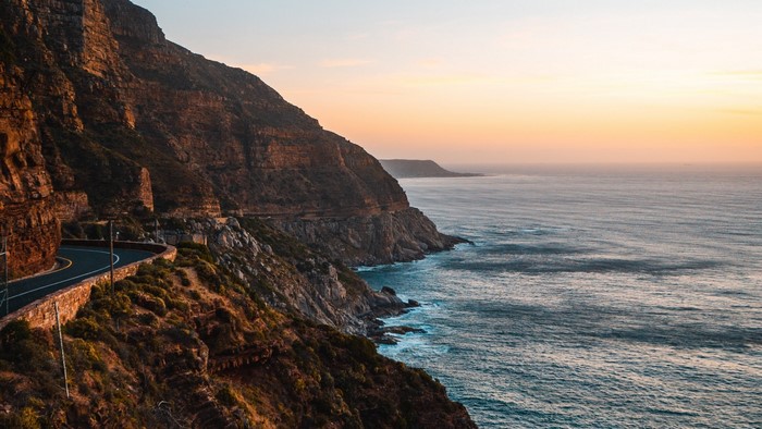 Coastal road along a cliff by the ocean at sunset