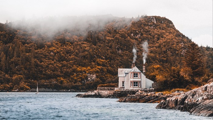 House on a rocky shore with a sailboat
