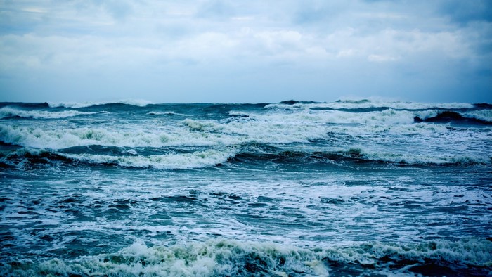 Ocean waves crashing under a cloudy sky