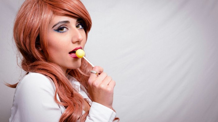 Woman with red hair eating a lollipop