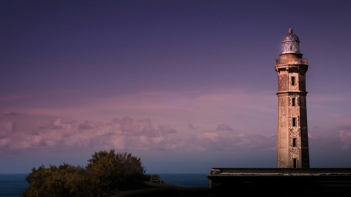 Lighthouse on a cliff overlooking the ocean at dusk
