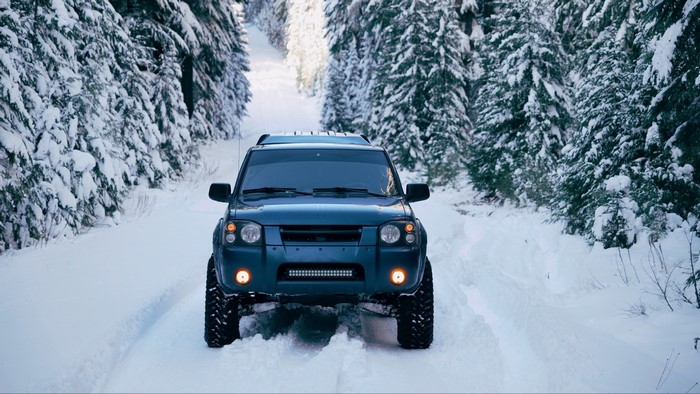 Blue SUV driving on a snowy forest road