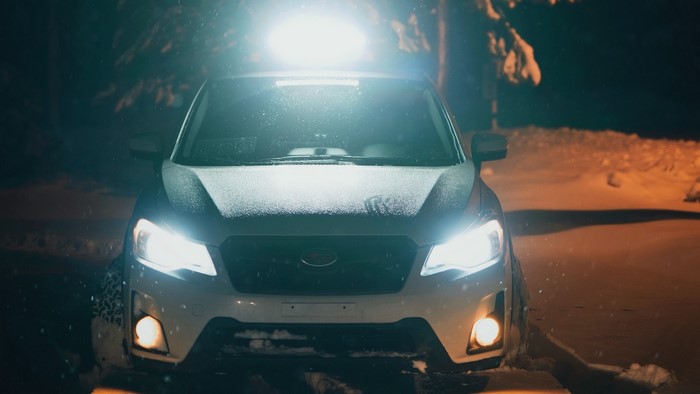 White Subaru Forester with light bar in snow at night