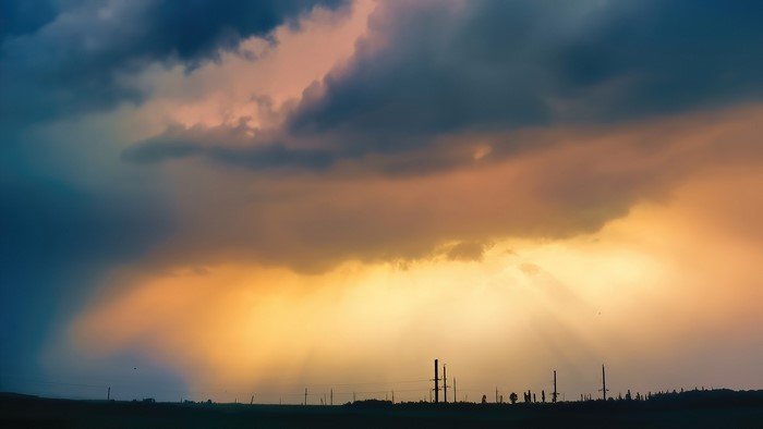 Stormy Sky with Sunbeams Over Silhouetted Landscape