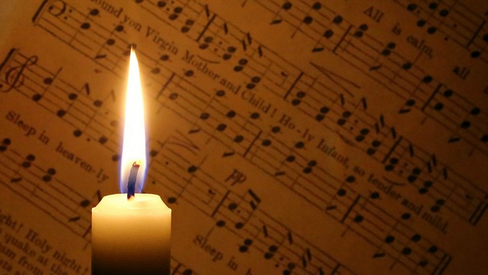 Candle burning in front of sheet music