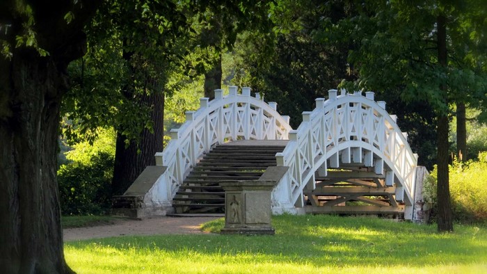 White arched bridge with stairs in a park