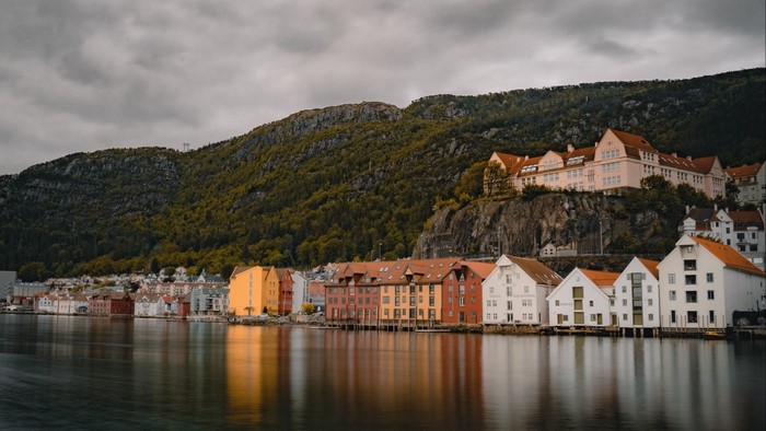 Colorful buildings on the waterfront with a forested mountain backdrop